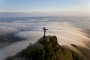 High angle view of colossal Christ Redeemer statue surrounded by clouds, Corcovado, Rio de Janeiro, Brazil.